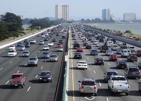 Typical congested traffic on an urban freeway – I-80 in Berkeley, California. Residents of U.S. cities typically require automobiles to experience mobility. Note the externalities that the drivers are imposing on others such as air pollution and congestion. The left lane is for car-pooling – as marked by the white diamond – an attempt to address the congestion externality.