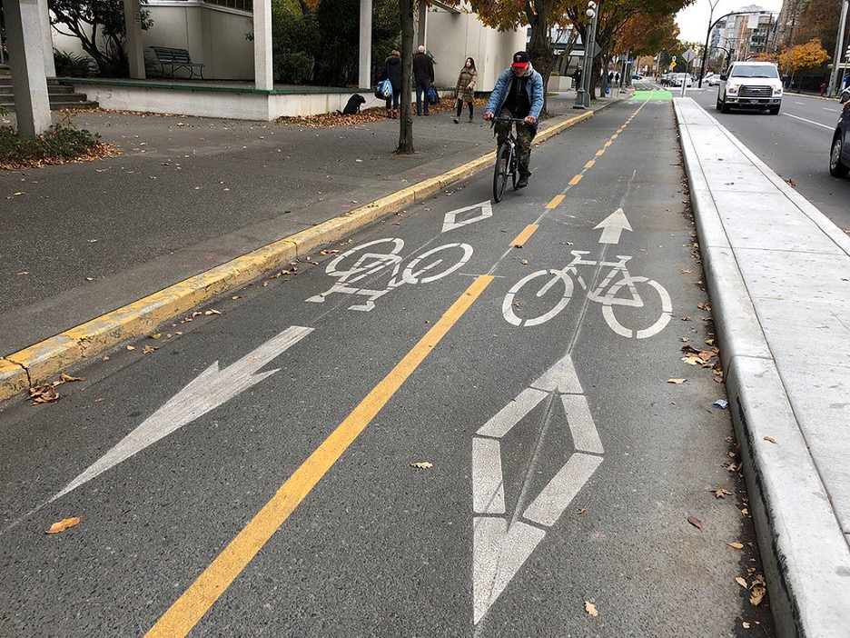 A two-way cycle track separated by a raised buffer between the motorized vehicle travel lane.