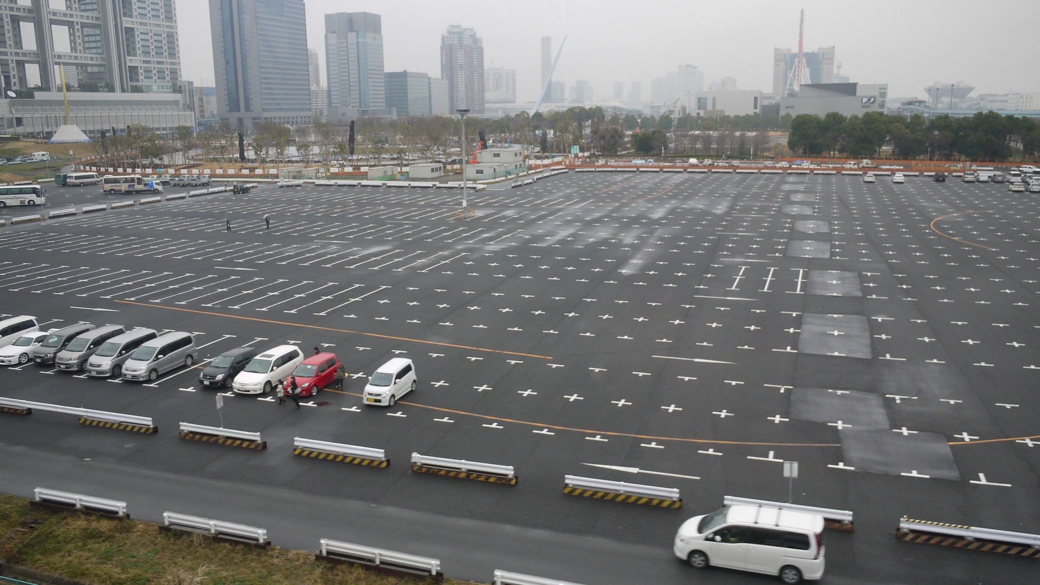 This picture shows a bird view of a giant but empty parking lot in an urbanized area.