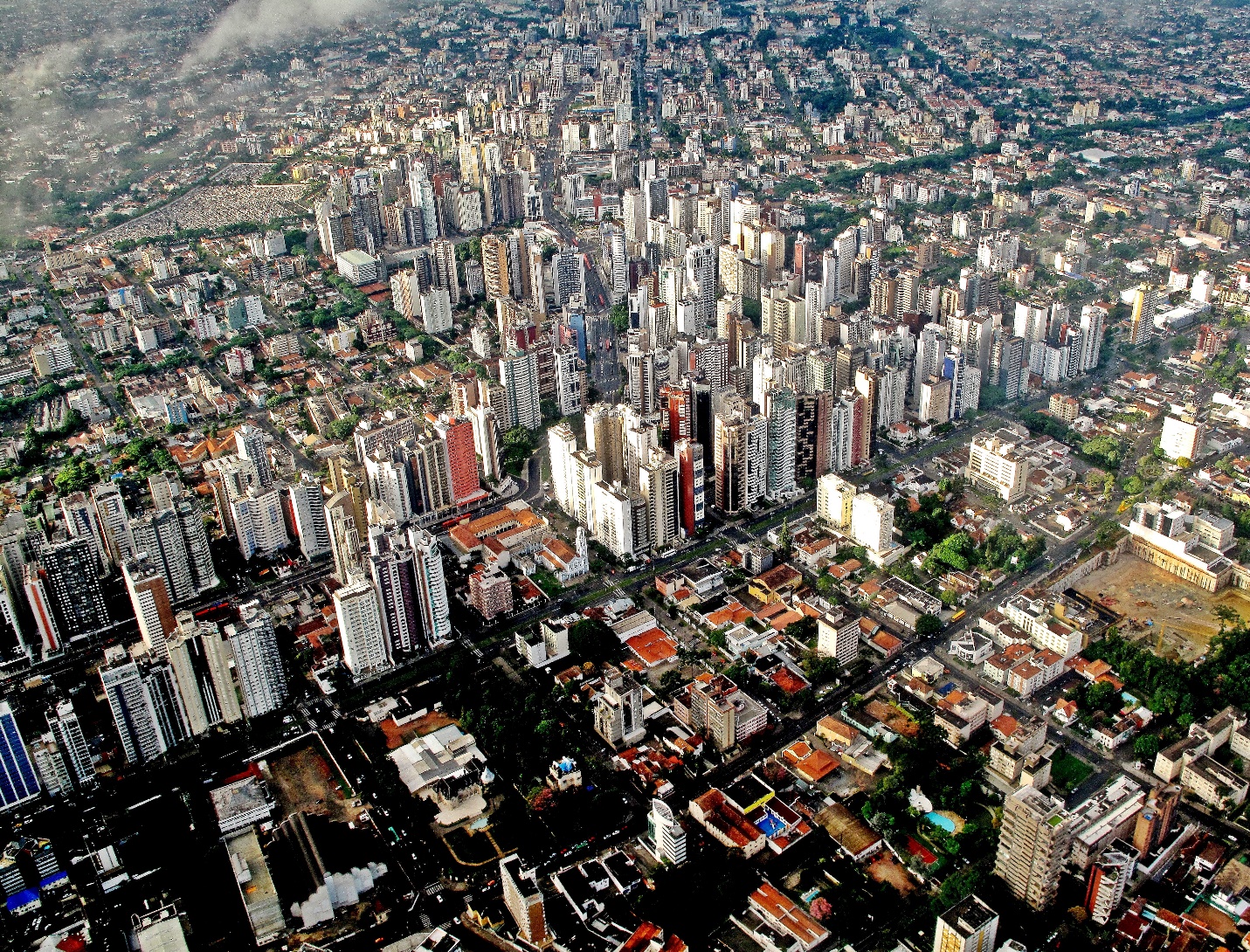 Downtown Curitiba, by Francisco Anzola, 2010 (https://upload.wikimedia.org/wikipedia/commons/e/e7/Curitiba_Centro.jpg). CC BY 2.0 https://creativecommons.org/licenses/by/2.0/deed.enThis photograph of Curitiba taken from the air shows high density, high-rise BRT corridors stretching in three directions, with what would be the fourth containing a lower density original downtown shown at the bottom of the image.