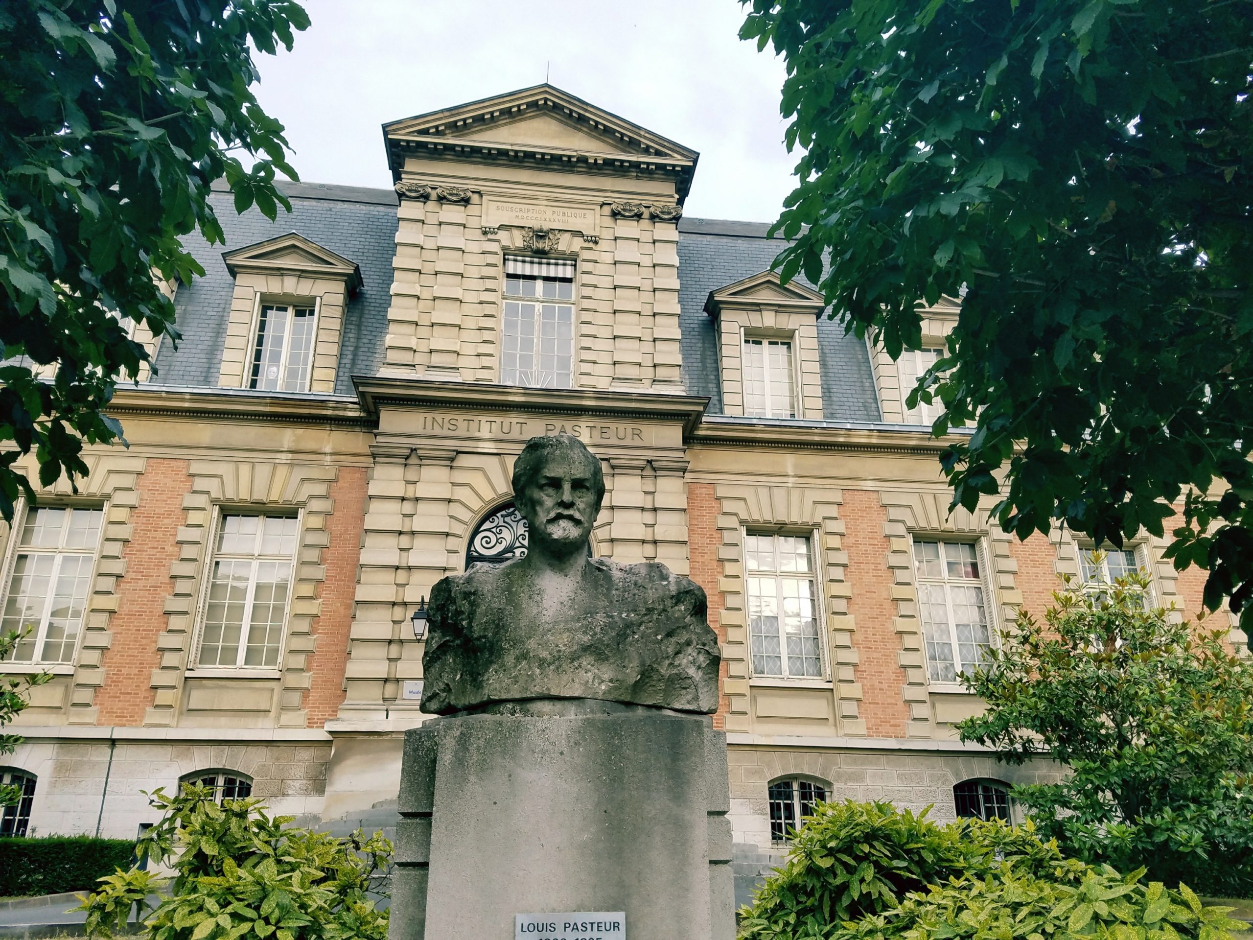 Stone bust of a man in front of a 19th century building