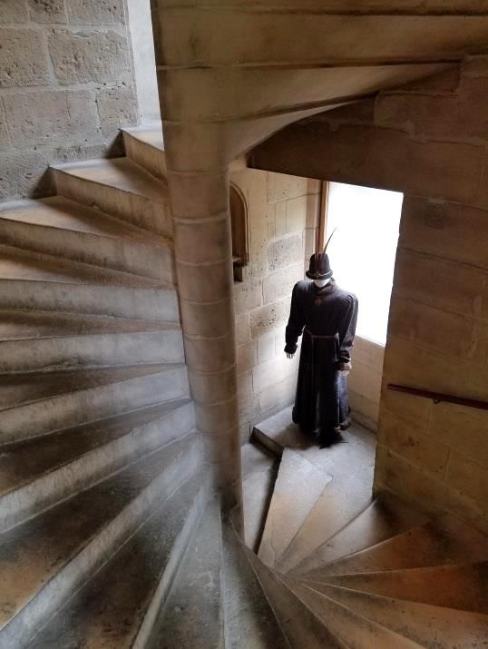 A mannequin in medieval dress stands on a medieval staircase