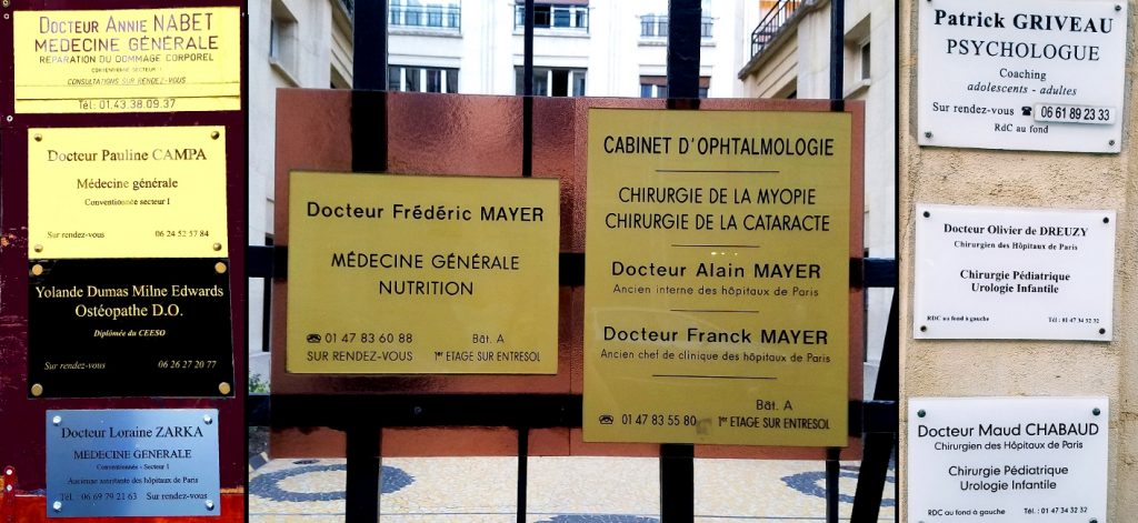 Signs indicating the specialization of various doctors, including (1) Docteur Annie Nabet, Dommage corporel (injuries), (2) Docteur Pauline Campa, Médecine générale, (3) Docteur Yolande Dumas Milne Edwards, Osteopathe D.O., (4) Docteur Loraine Zarka, Médicine générale, (5) Docteur Frédéric Mayer, Nutrition, (6) Docteurs Alain Mayer and Franck Mayer, Chirurgerie de la myopie et de la cataracte (Cataract and Nearsightedness surgery), (7) Patrick Griveay, Psychologue, (8) Docteurs Olivier de Dreuzy and Maud Chabaud, Chirurgie pédiatrique et urologie infantile