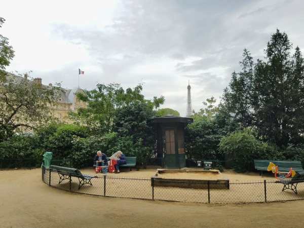 Clouds envelop the Eiffel Tower seen at the distance behind a park