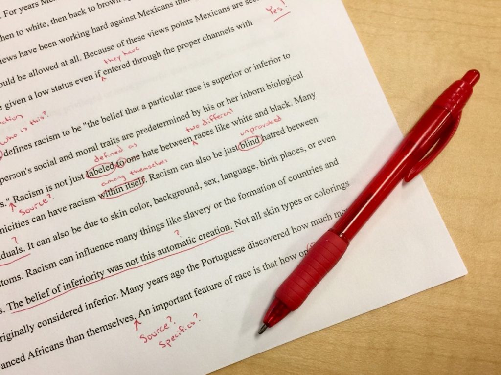 a typewritten paper with corrections in red ink written on it